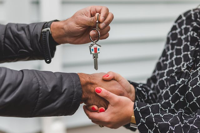 two people shaking hands and exchanging keys
